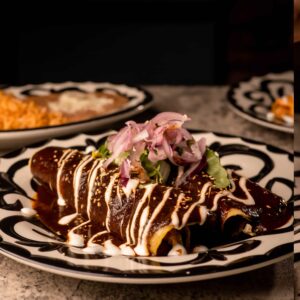 Mariposas Enchiladas de Mole: 2 enchiladas, shredded chicken, mole casero sauce, shredded lettuce, crema, lime onions, rice, beans.