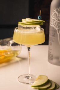 Mariposas Manzana con Chile cocktail garnished with green apple, serrano chile, and fresh basil.