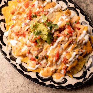 Mariposas Nachos: queso blanco, beans, pico, avo mash, crema, chipotle crema +meat $4 extra.