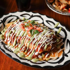 Mariposas Burrito Mojado covered with red and green salsa, crema, pico de gallo, and fresh cilantro.