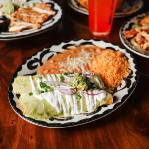 Mariposas enchiladas verdes with green salsa, crema, guacamole, and red onion, served with Mexican rice and refried beans.