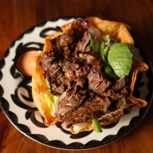 Mariposas Mariposa Salad with grilled steak, romaine, avocado, pico de gallo, bell pepper, and red cabbage in a crisp tortilla bowl.