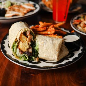 Mariposas Chicken Caesar Wrap with romaine, Parmesan, and croutons, served with sweet potato fries and dipping sauce.